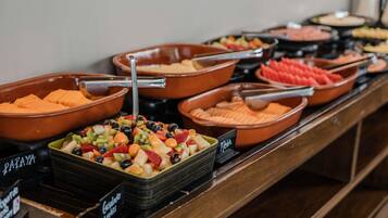 A buffet with various food options including fruits and meats.