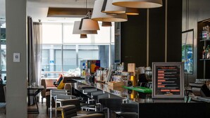 A modern bar area with multiple seating options, a menu board, and a large window providing natural light.