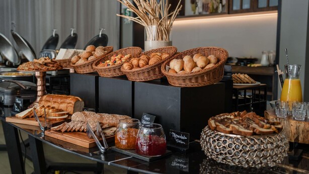 A breakfast buffet with various breads, pastries, and jams.