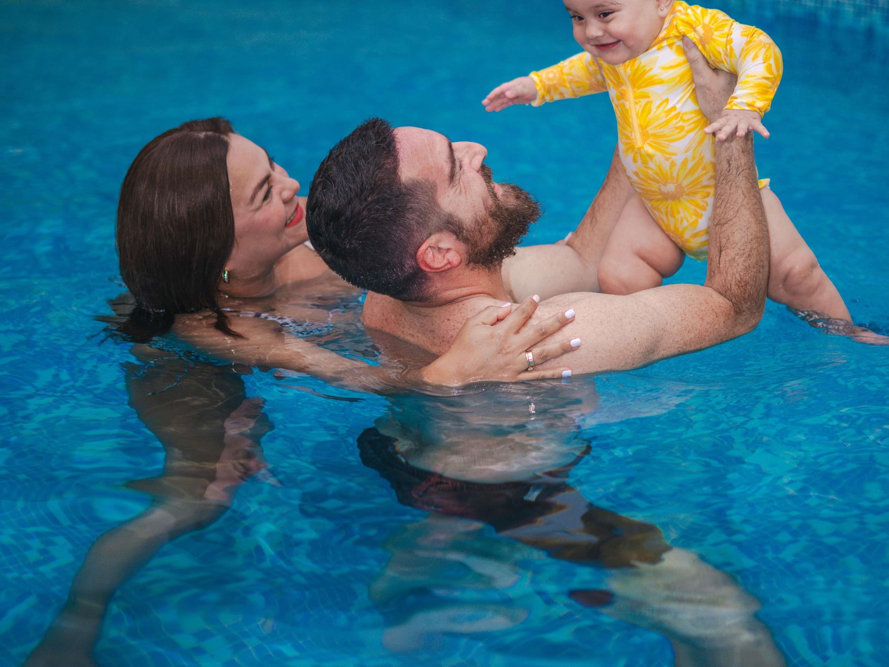 Una familia en una piscina con agua azul cristalina.
