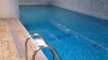 Una piscina techada, sillones reclinables de piscina