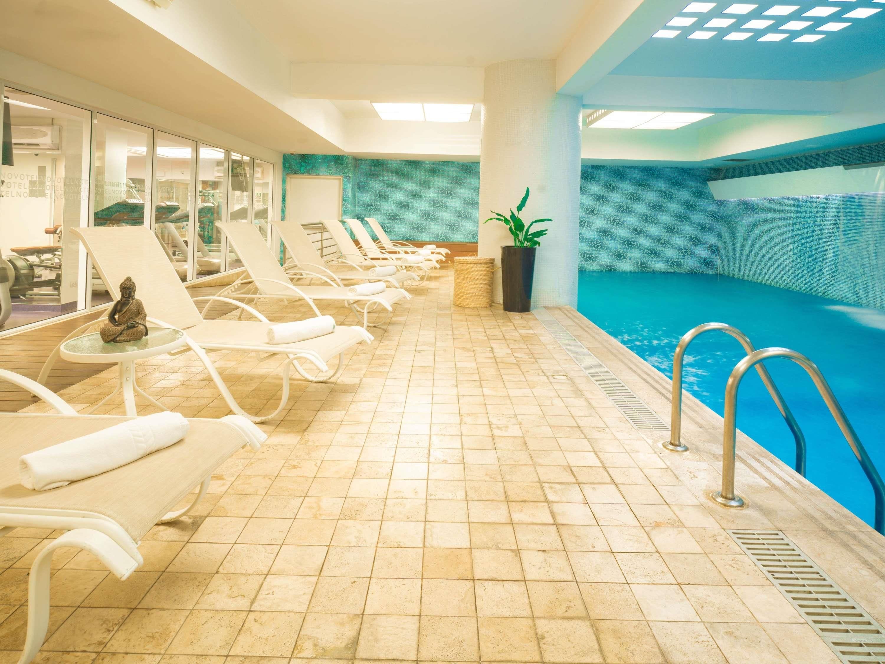 A poolside area with sun loungers, a Buddha statue, and a tiled floor.