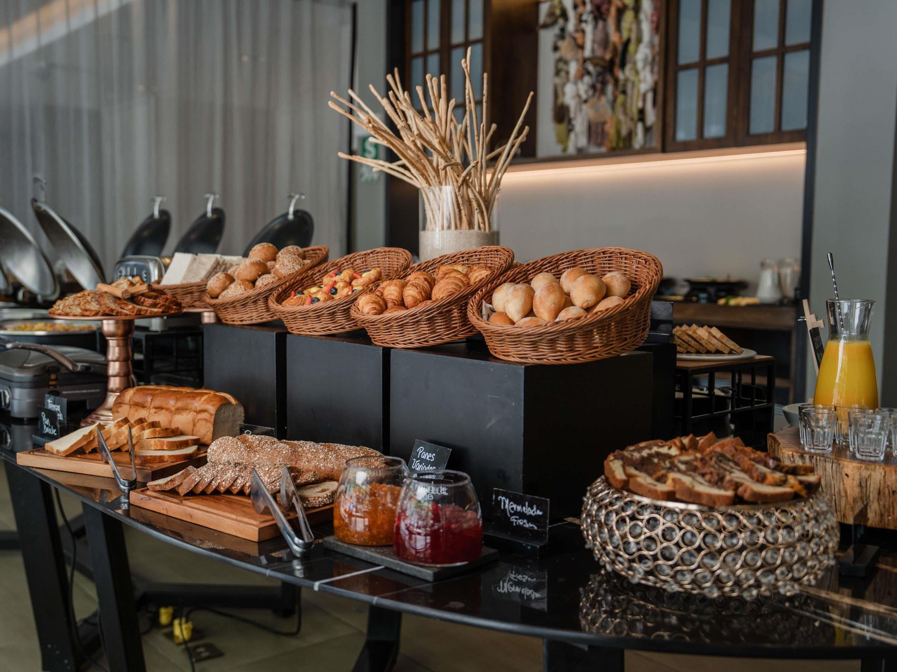 A breakfast buffet with various breads, pastries, and jams.
