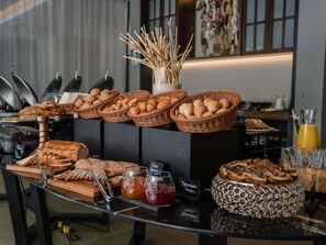 Un bufé de desayuno con panes, pasteles y mermeladas variadas.