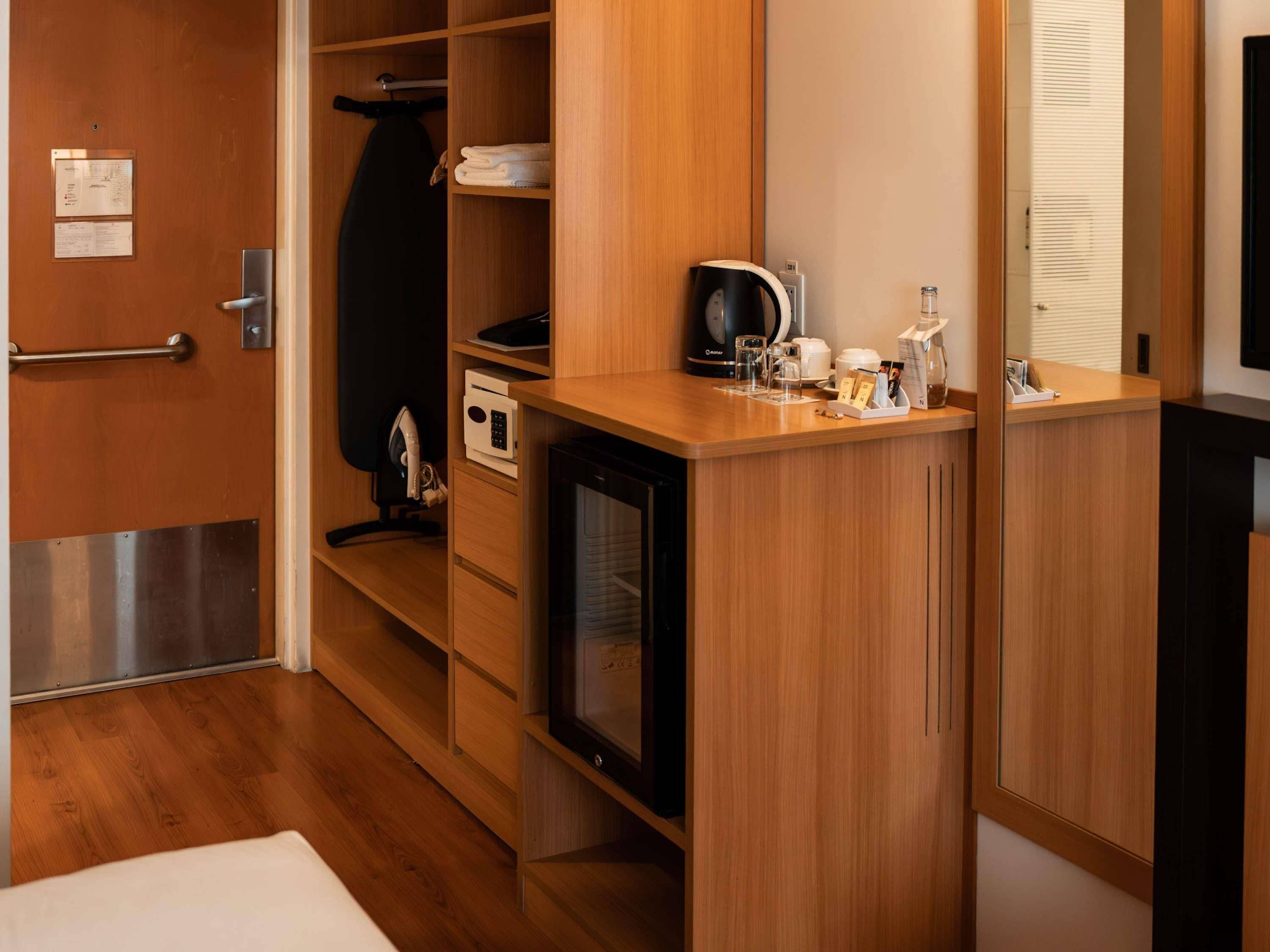 Habitación de hotel compacta con kitchenette, un refrigerador pequeño, microondas, cafetera y televisor.