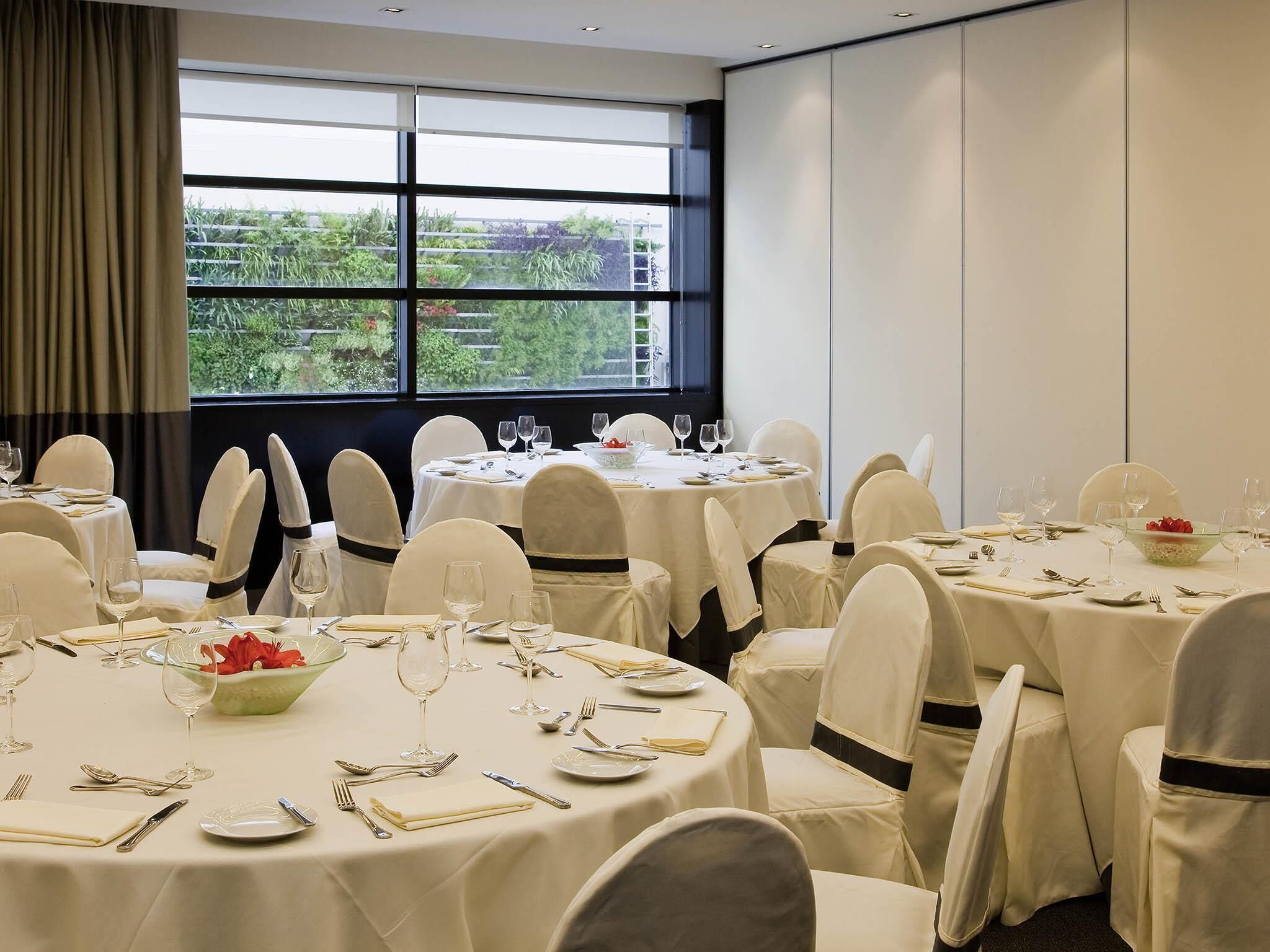 A banquet hall with round tables, white tablecloths, and chairs with black sashes.