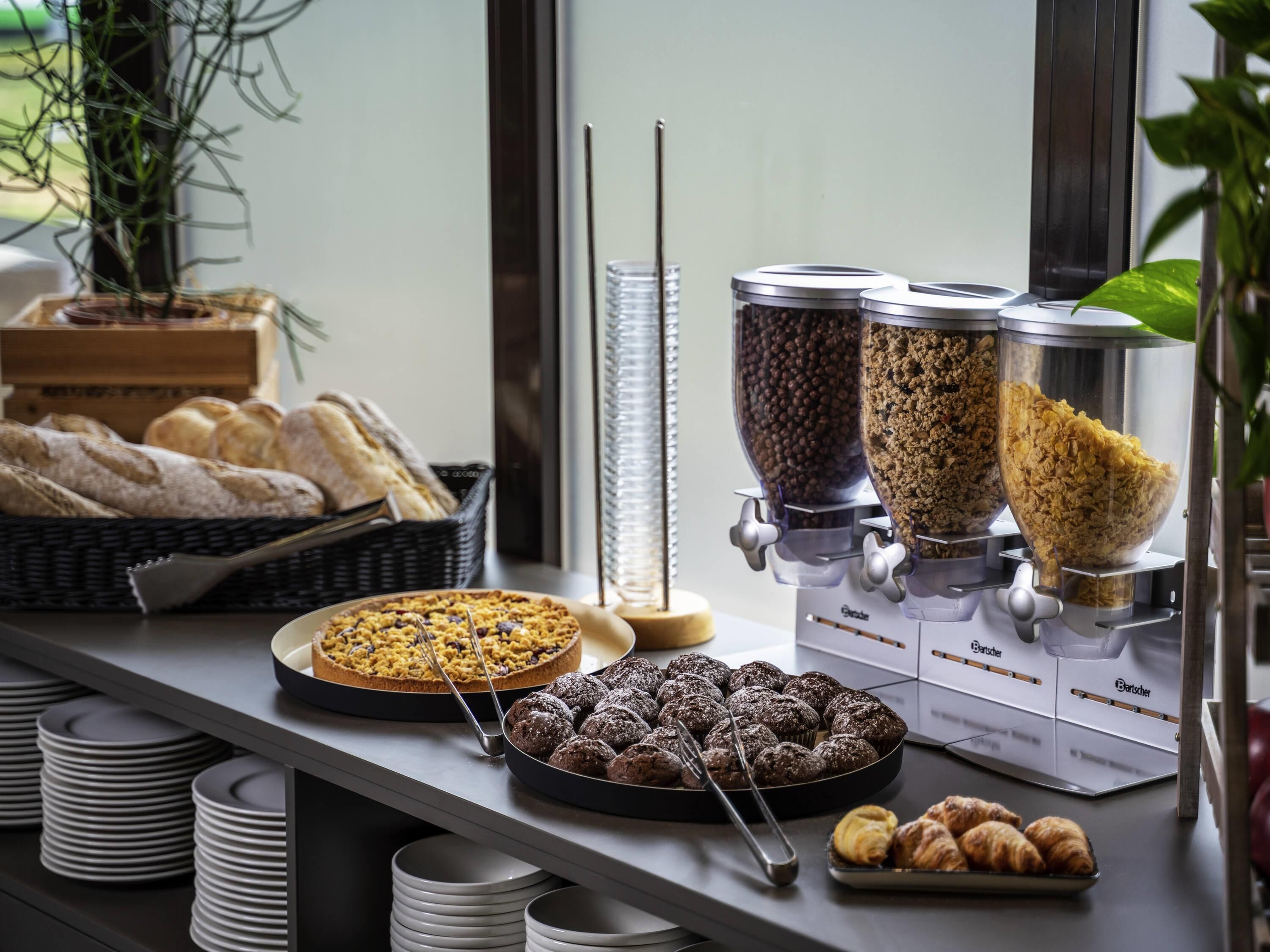 Un buffet proposant une variété de plats, notamment une tarte, des boules au chocolat et des croissants.