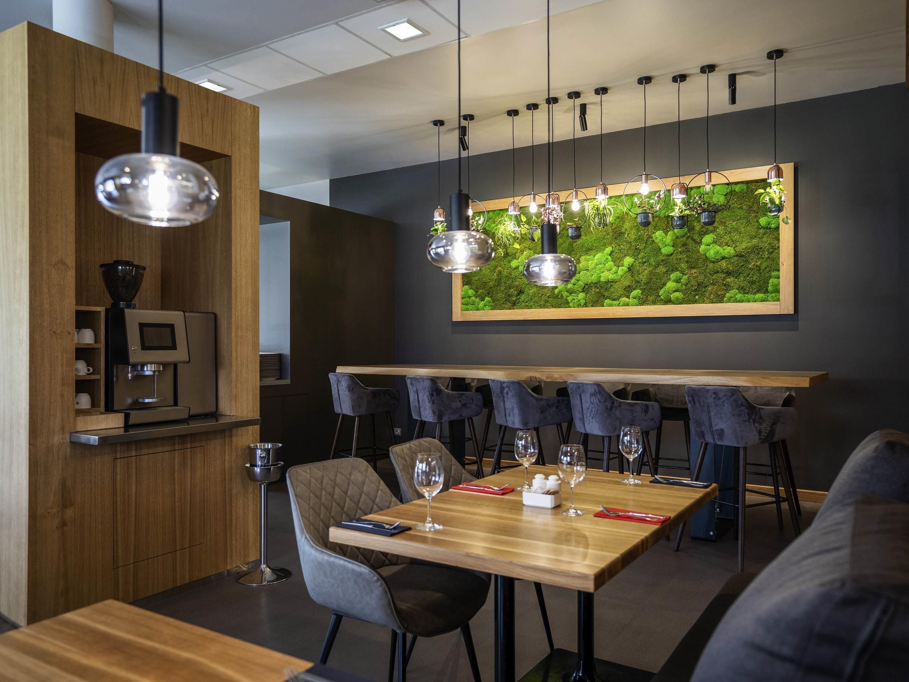 A modern dining area with a wooden table, cushioned chairs, and a coffee machine.