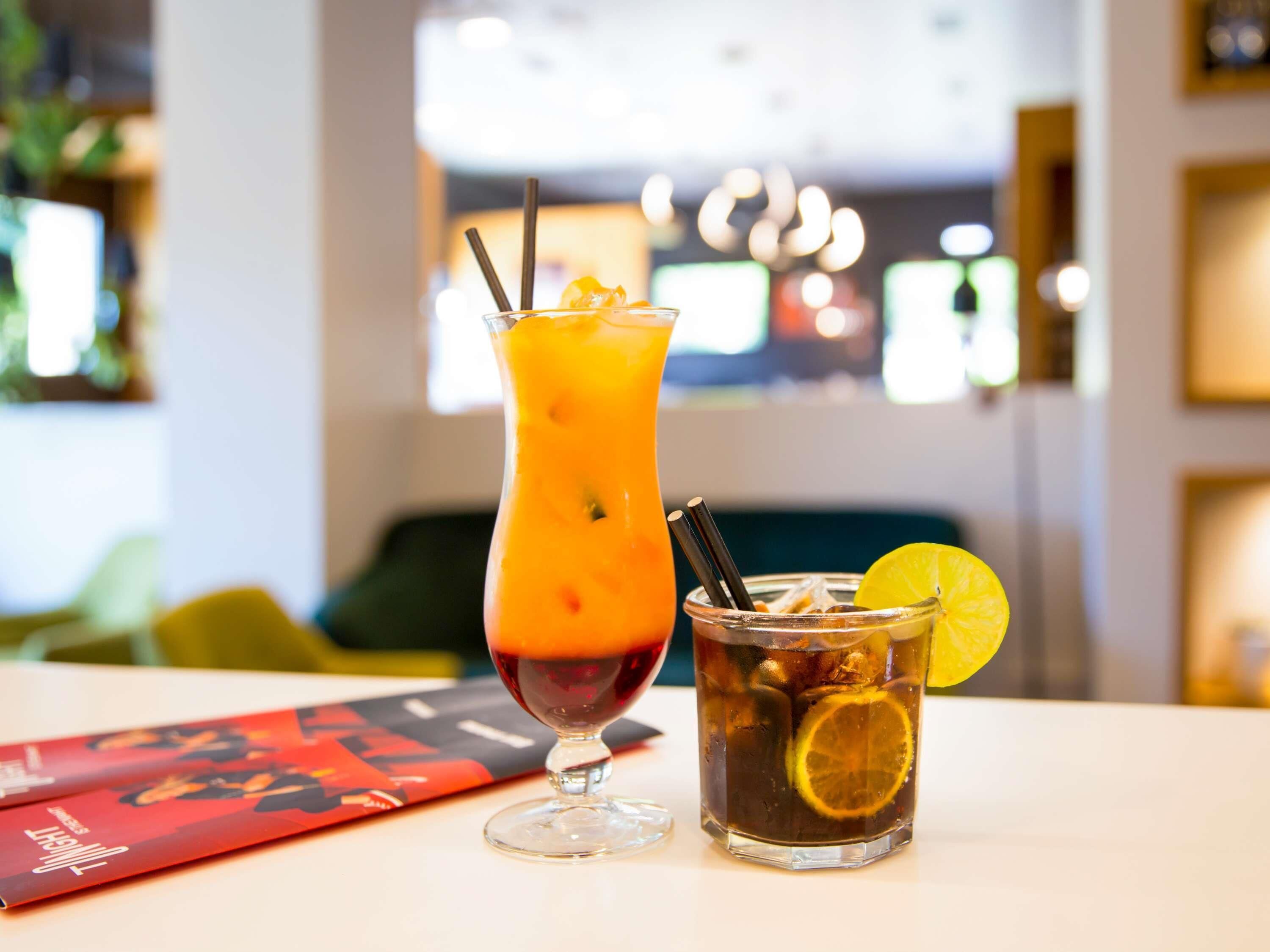 Duas bebidas sobre uma mesa, com um menu e fundo desfocado.