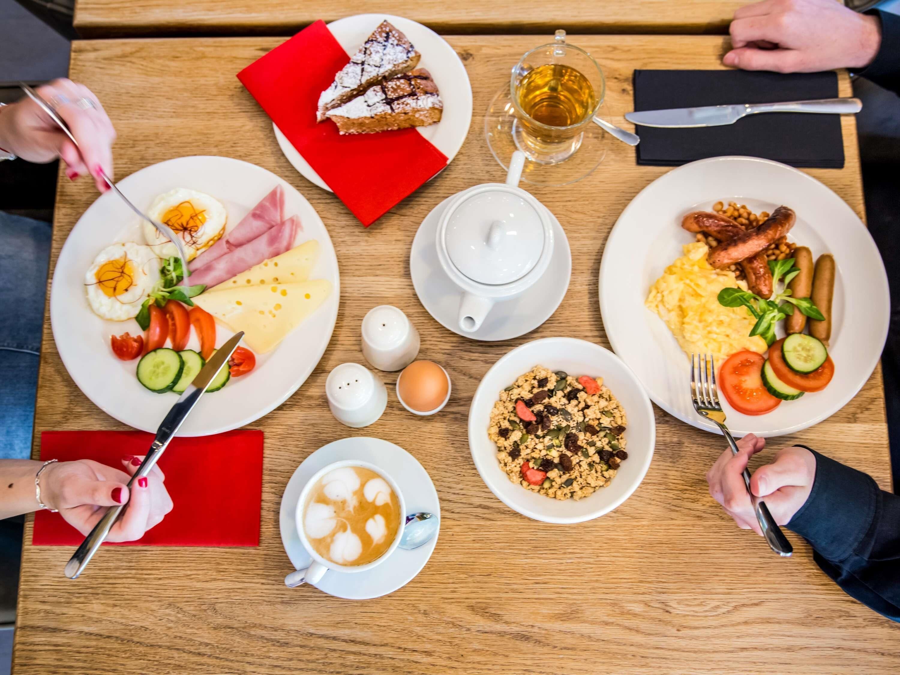 A table set with breakfast plates, a cup of coffee, and a teapot.