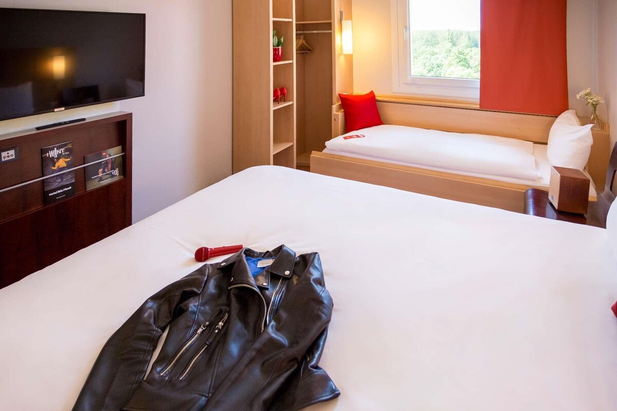 Habitación de hotel con cama, televisión, armario y ventana con vistas.