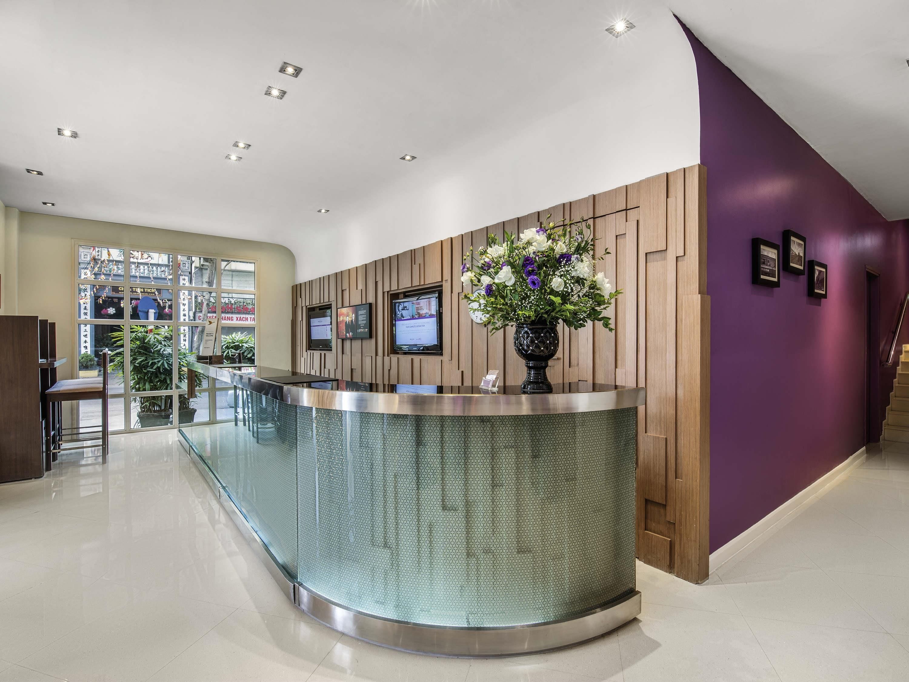 Un espace d’accueil doté d’un comptoir en verre incurvé, d’un mur revêtu de panneaux en bois et d’un mur d’accent de couleur violette.