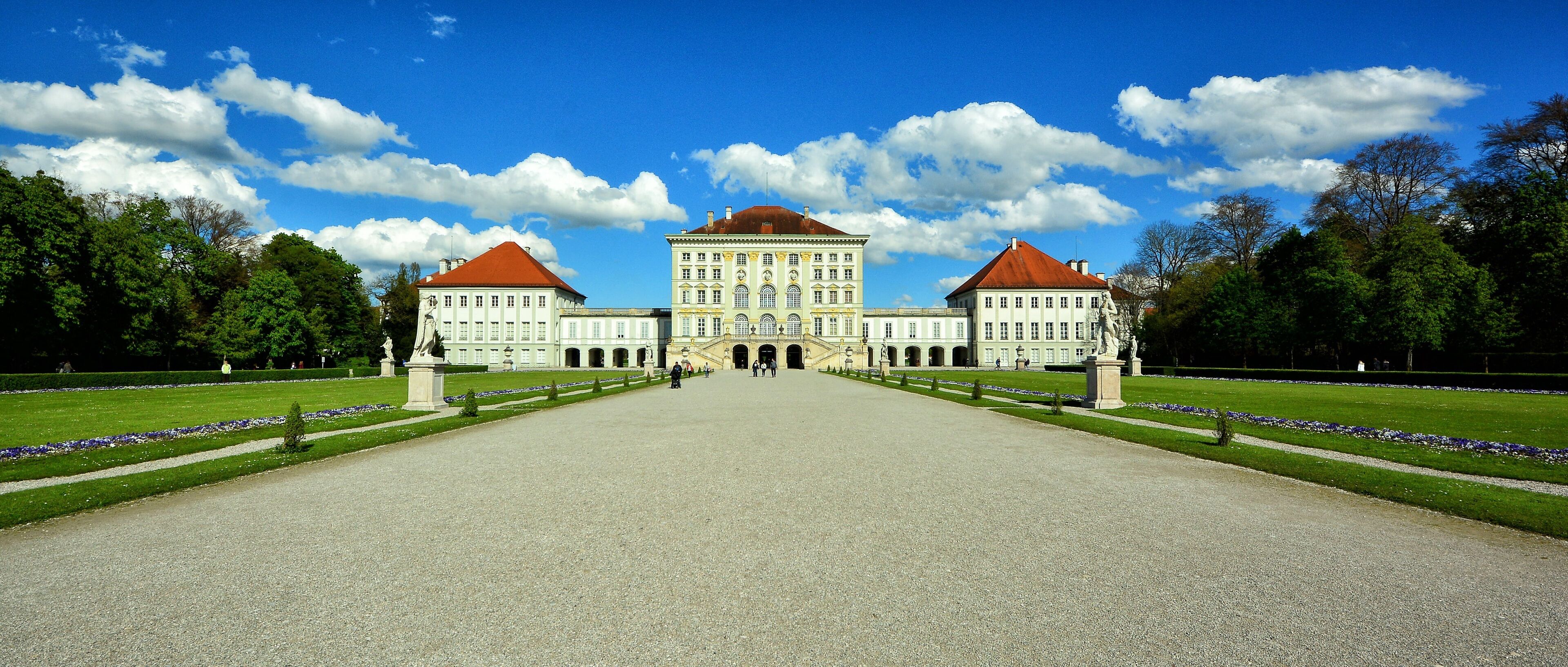 A large, symmetrical building with a central entrance and two wings, surrounded by well-manicured lawns and trees.