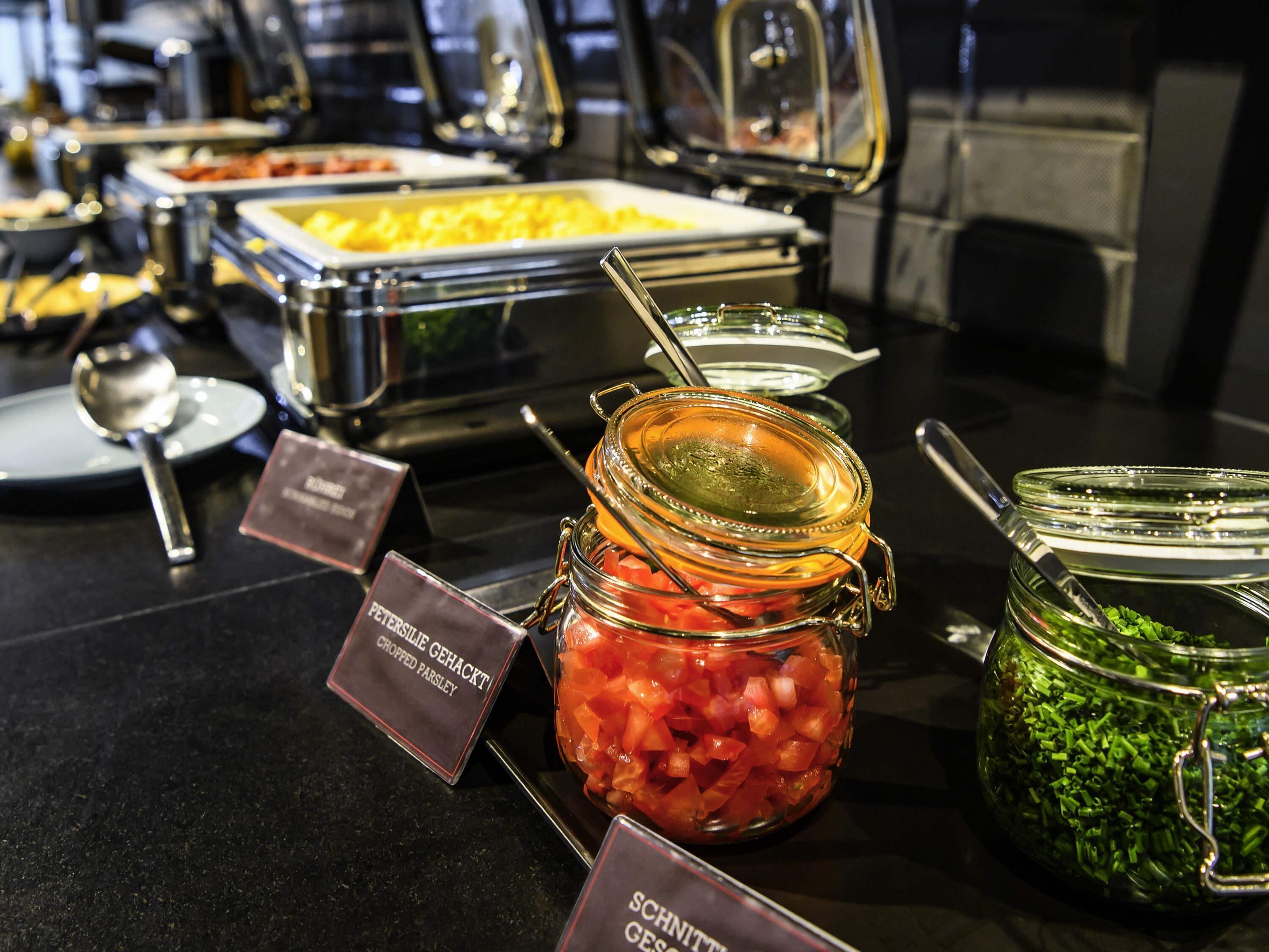 A buffet with various food items including chopped parsley, tomatoes, and green onions.