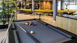 A pool table with balls in a modern indoor setting with seating and plants. - ibis Muenchen City West (Munich)