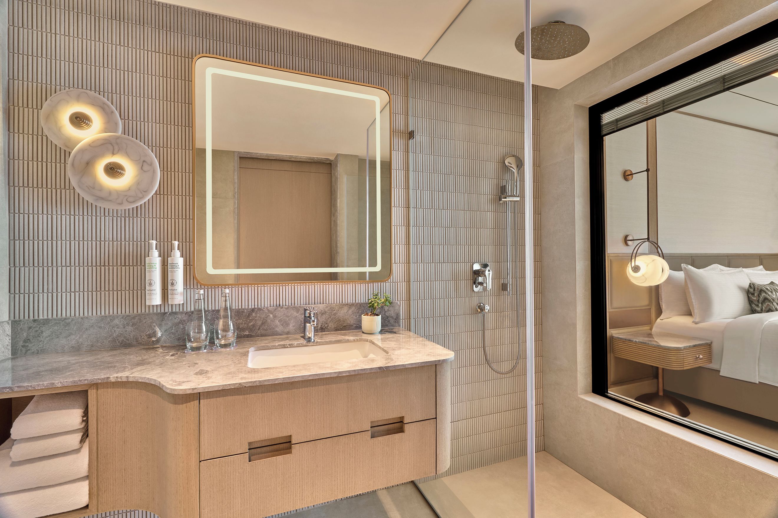 A modern bathroom with a large mirror, a sink, and a shower.