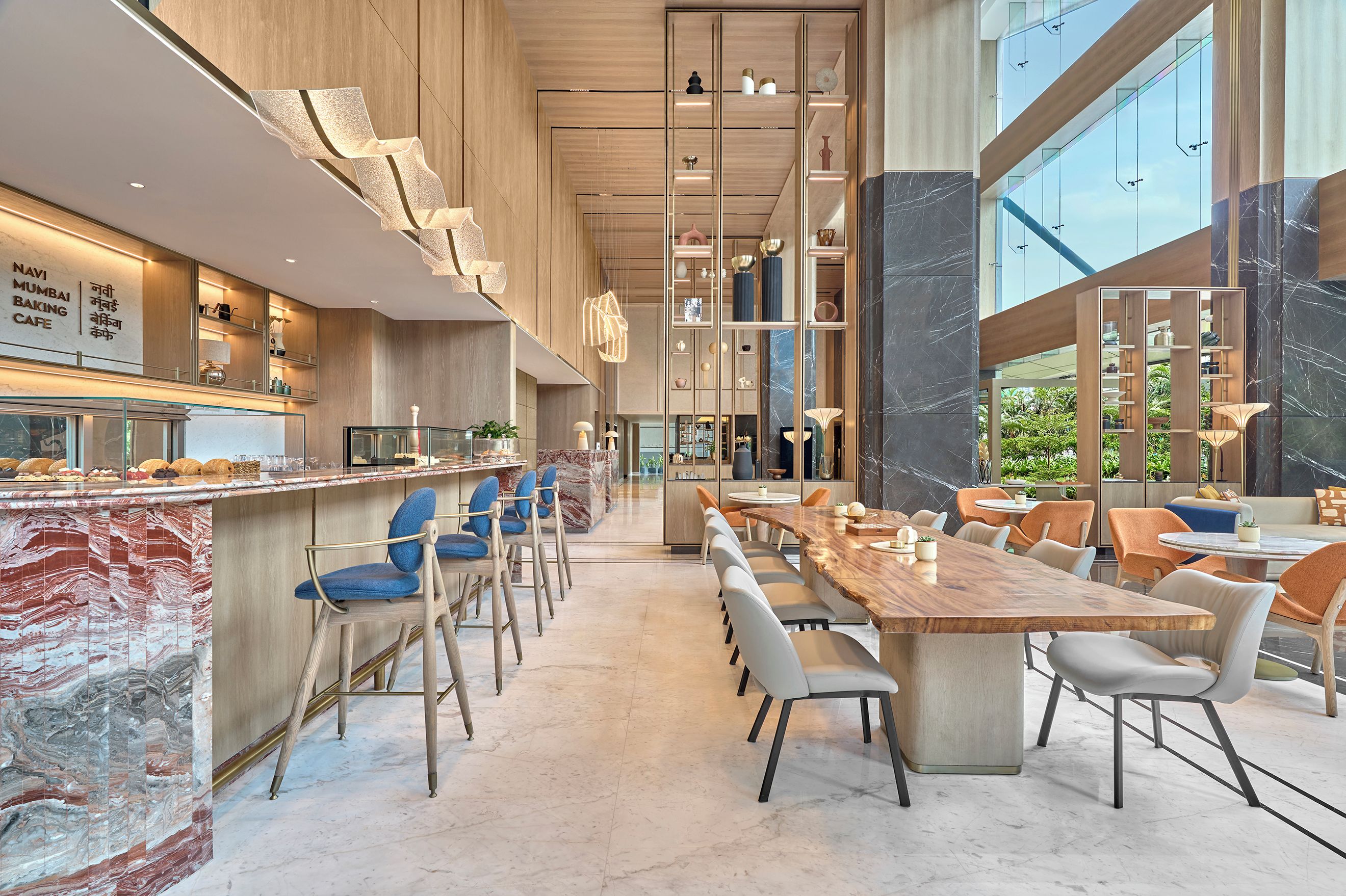 Interior moderno de una cafetería con una barra larga, zona de estar y amplias ventanas.