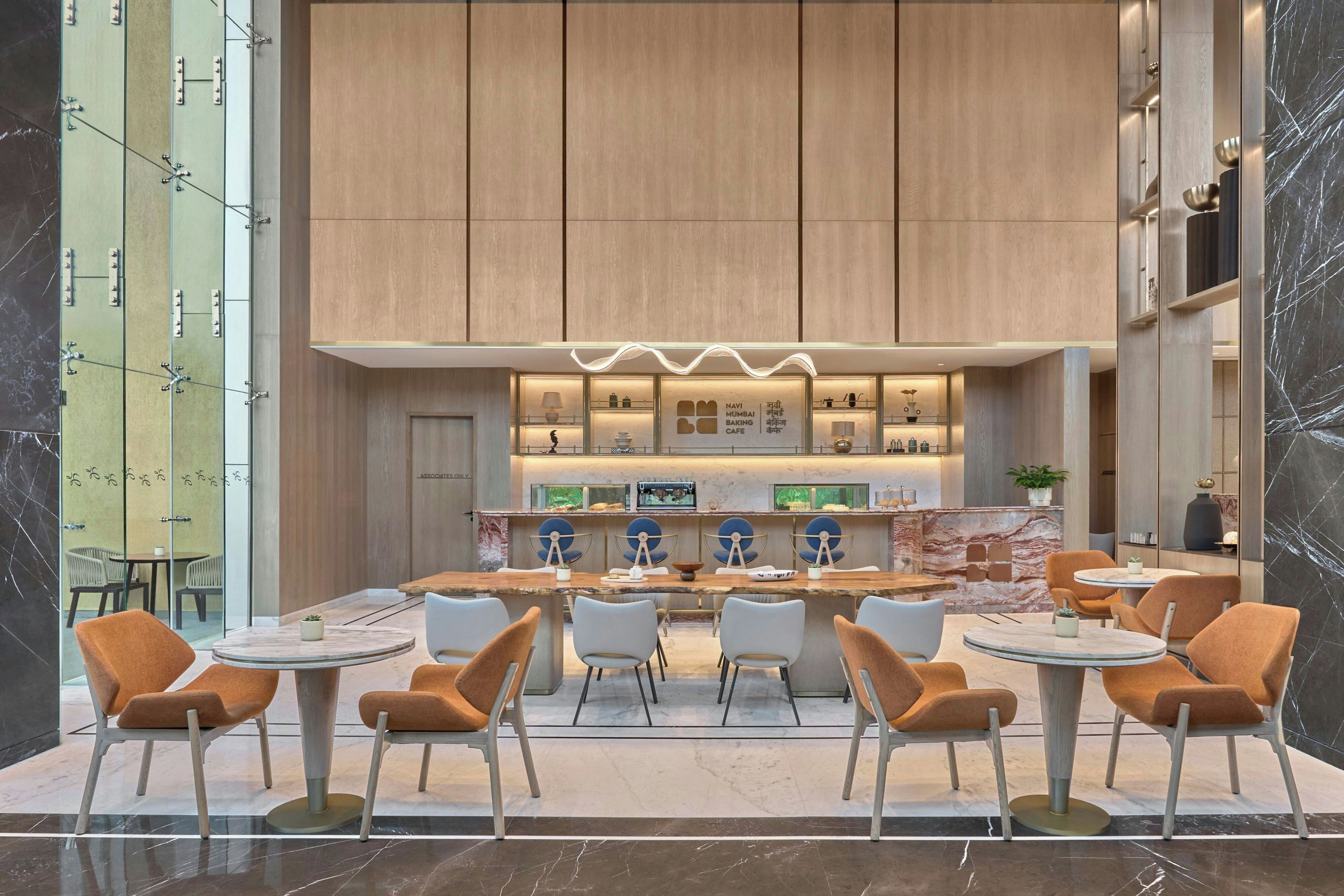 A modern cafe with a central bar, seating area with round tables and chairs, and a marble-tiled floor.