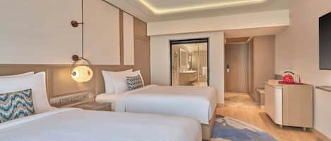 A hotel room with two beds, a bathroom, and a kitchenette.