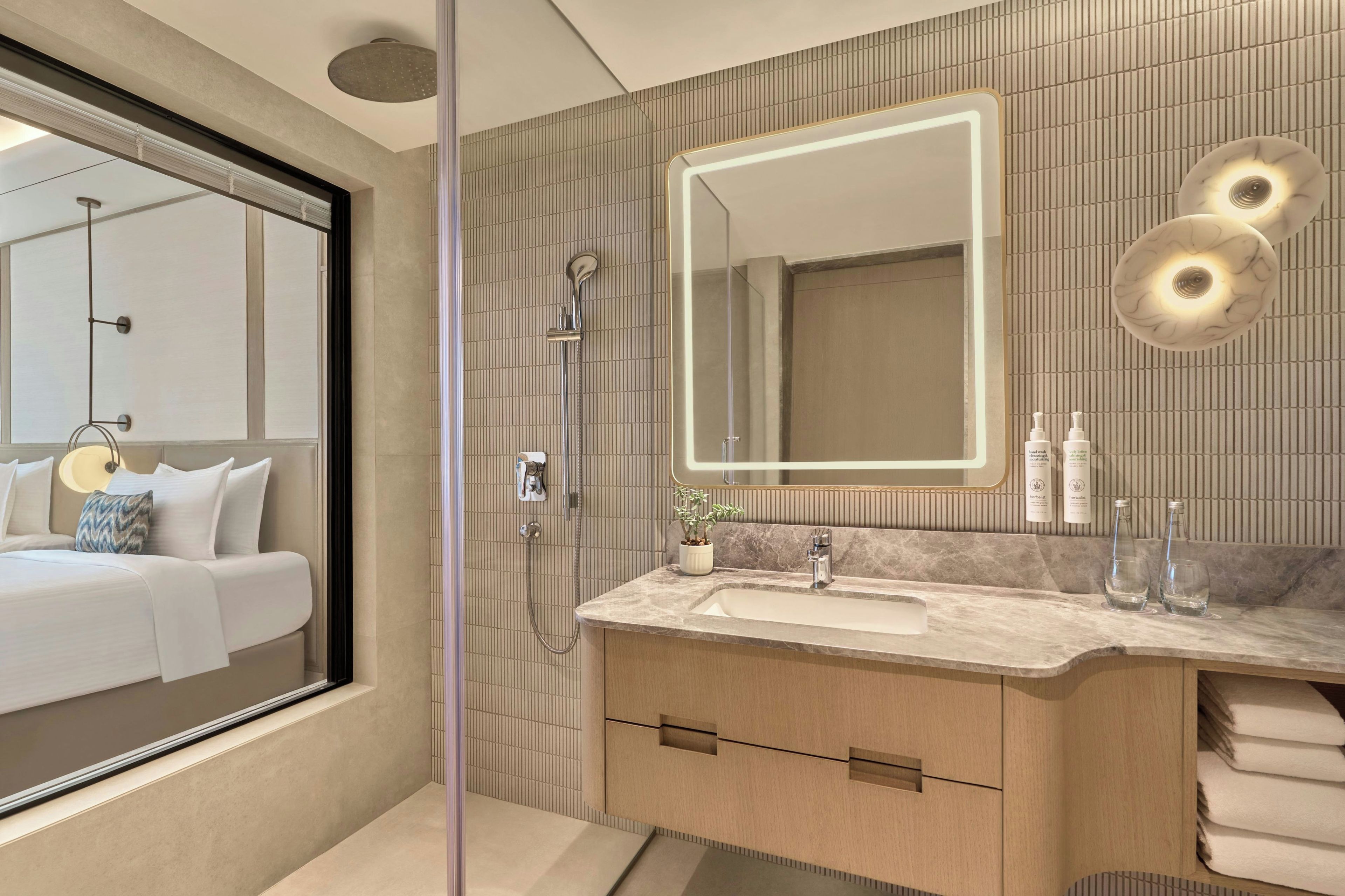 Un baño moderno con un espejo grande, ducha y tocador con lavamanos.