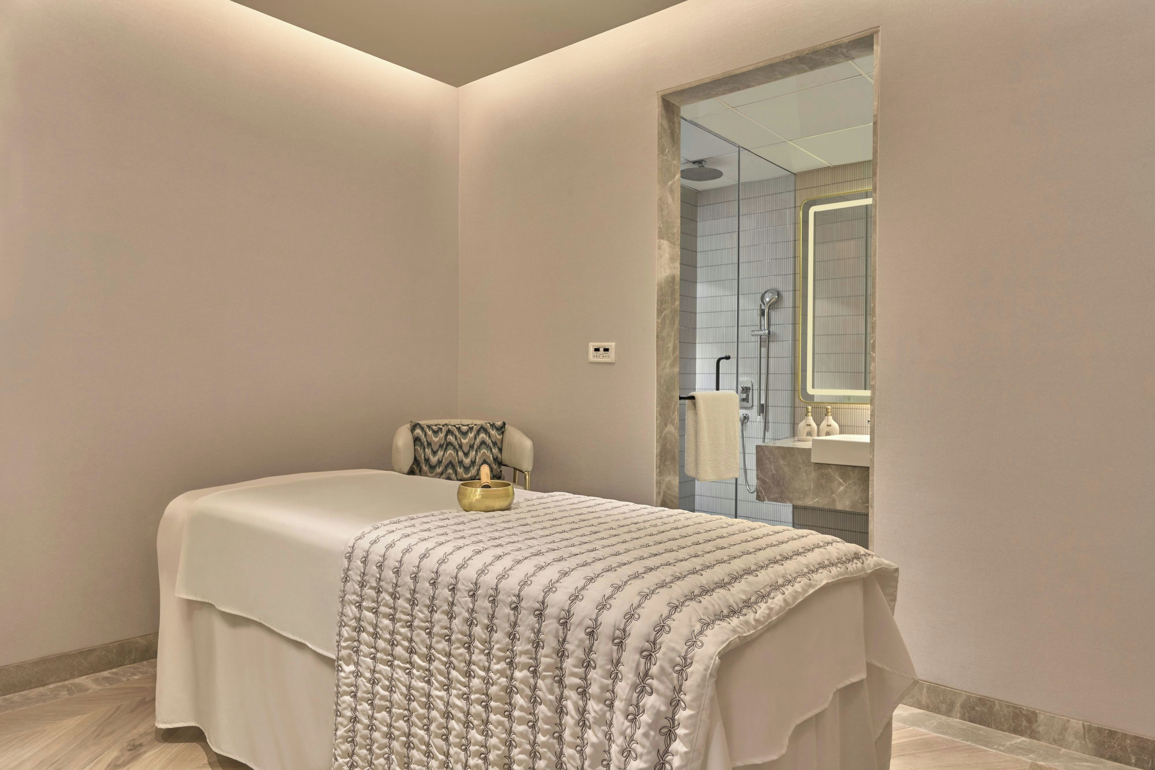 A modern bedroom with a large bed, a massage table, and a small meditation area with a bowl.