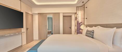 A modern hotel room with a large bed, a flat-screen TV, and a view of the hallway.