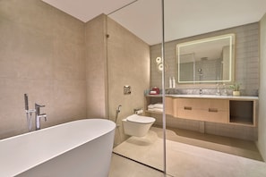 Un baño moderno con una bañera independiente, inodoro y tocador con espejo.