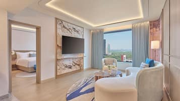 A modern hotel room with a bed, seating area, flat-screen TV, and a city view.