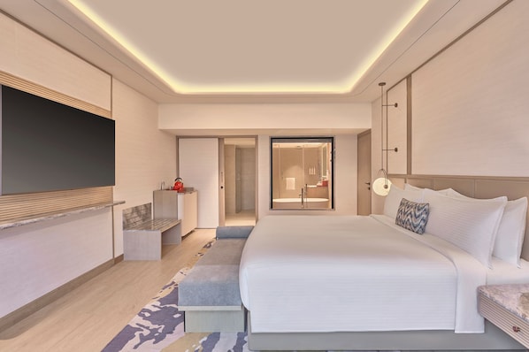 Habitación de hotel moderna con una cama grande, televisor de pantalla plana, escritorio y zona de ducha.