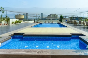 A rooftop swimming pool with a city view, surrounded by potted plants and outdoor seating. - Athiva Pulse Navi Mumbai, Autograph Collection (Navi Mumbai)