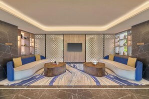 A modern living room with a curved sofa set, two round coffee tables, a patterned rug, and a wall-mounted TV.
