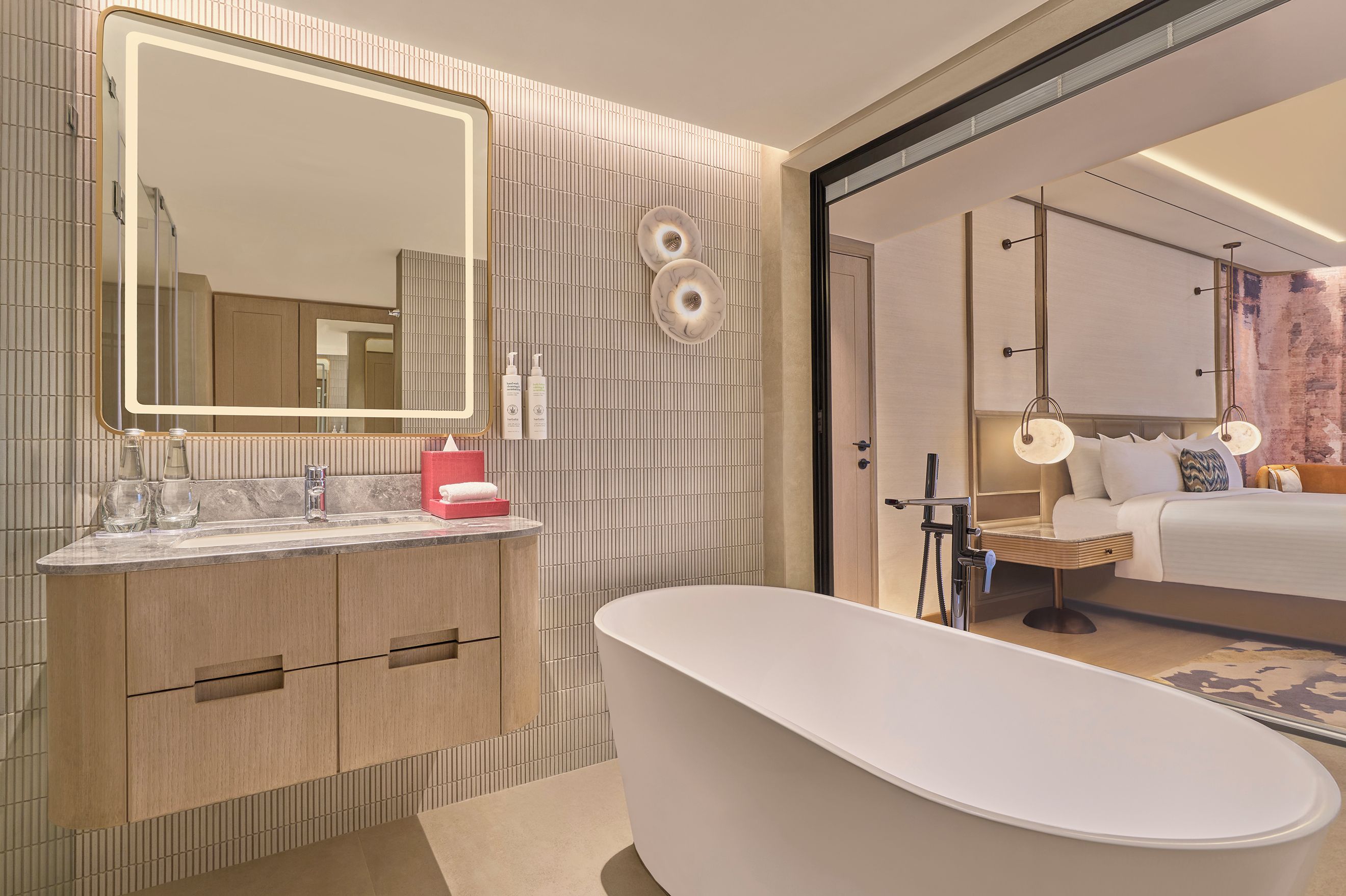 Un baño moderno con una bañera independiente, un espejo grande y un tocador con encimera de mármol.