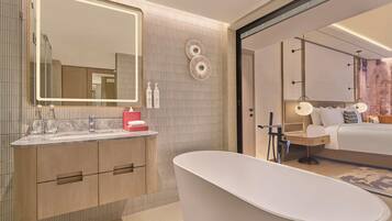 Un baño moderno con una bañera independiente, un espejo grande y un tocador con encimera de mármol.