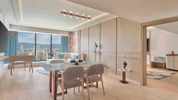 A modern living room with a dining area, large windows, and a view of the cityscape.