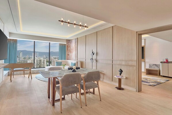 A modern living room with a dining area, large windows, and a view of the cityscape.