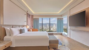 A modern hotel room with a large bed, a seating area, a TV, and a city view. - Athiva Pulse Navi Mumbai, Autograph Collection (Navi Mumbai)