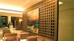 Un hall con zonas de estar, un mostrador de recepción y un cuadro abstracto grande en la pared.