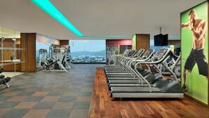 Ein Fitnessstudio mit Laufbändern, Kraftgeräten und Blick auf die Stadt.