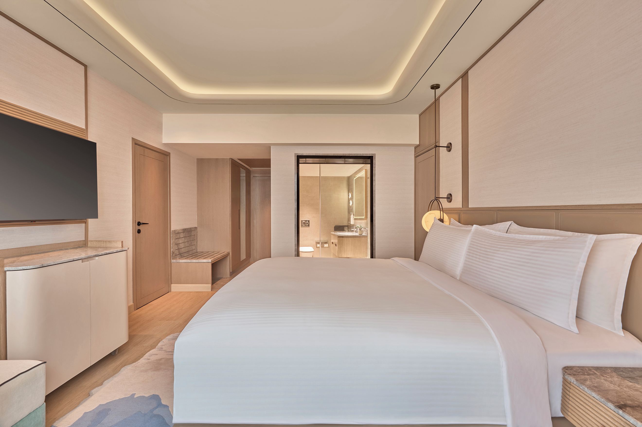 A modern hotel room with a large bed, a flat-screen TV, and a walk-in closet.