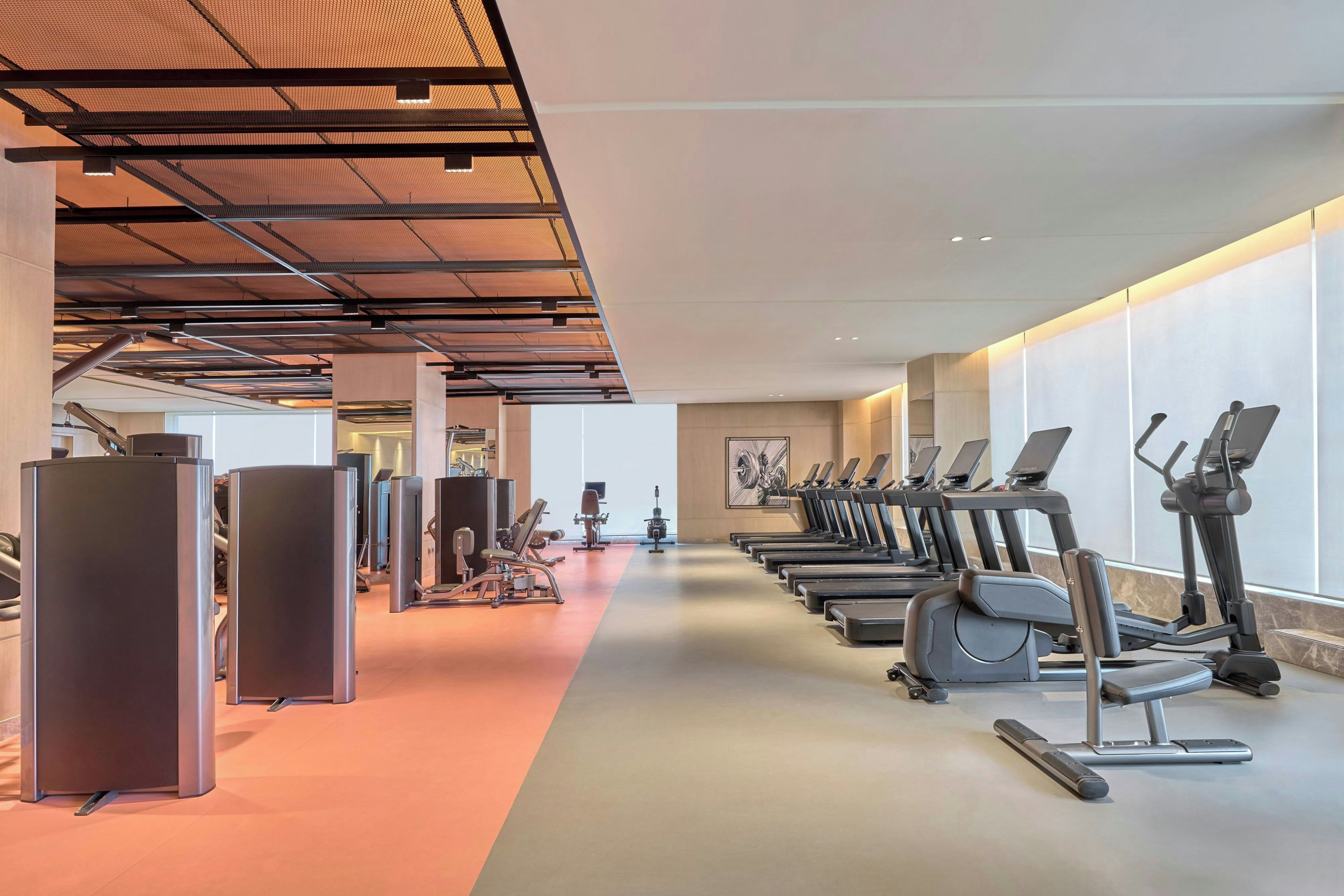 A gym with exercise equipment, including treadmills and weight machines, and a long corridor.