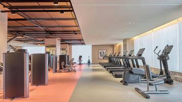A gym with exercise equipment, including treadmills and weight machines, and a long corridor.