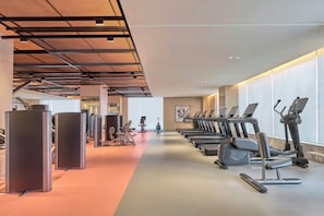 A gym with exercise equipment, including treadmills and weight machines, and a long corridor.