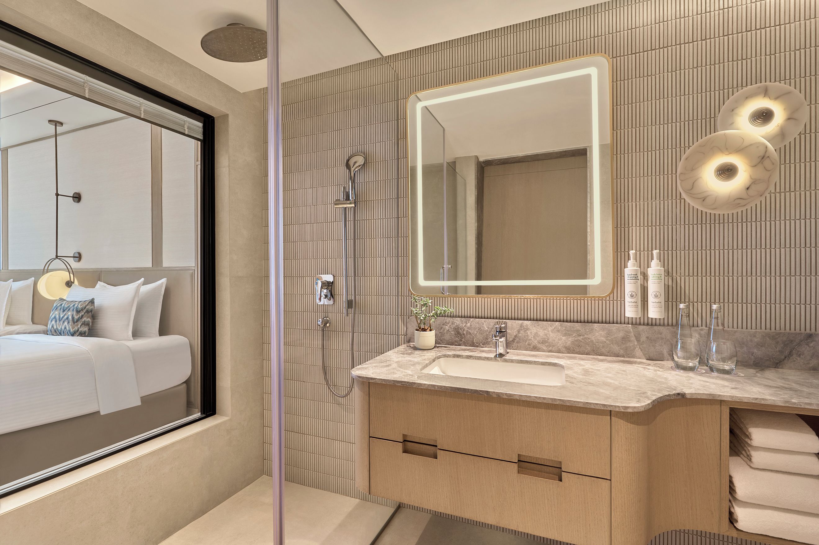 A modern bathroom with a large mirror, a shower, a sink, and a vanity.