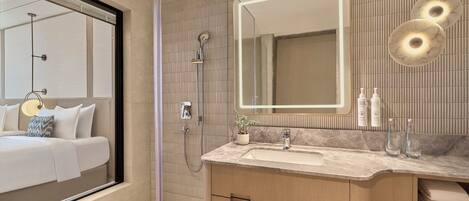 A modern bathroom with a large mirror, a shower, a sink, and a vanity.