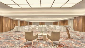 A spacious conference room with round tables, white chairs, and a patterned carpet.