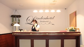 Een receptiebalie bij het Lindenhotel, met een bordje met de tekst 'Lindenhotel Stralsund'.
