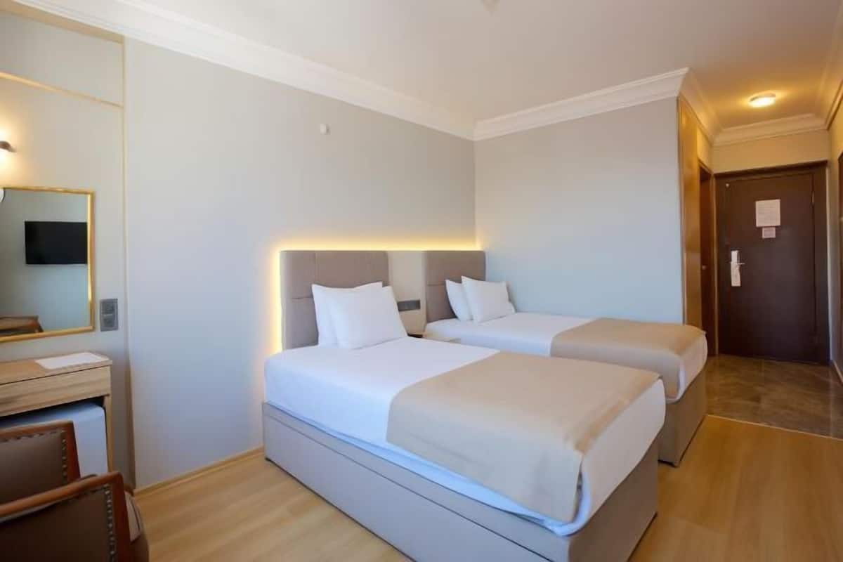 Habitación de hotel con dos camas, un escritorio y un espejo.