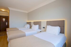 A hotel room with three single beds, a wooden floor, and a door with a sign. - Palette Grand Ant Hotel Istanbul (Istanbul)