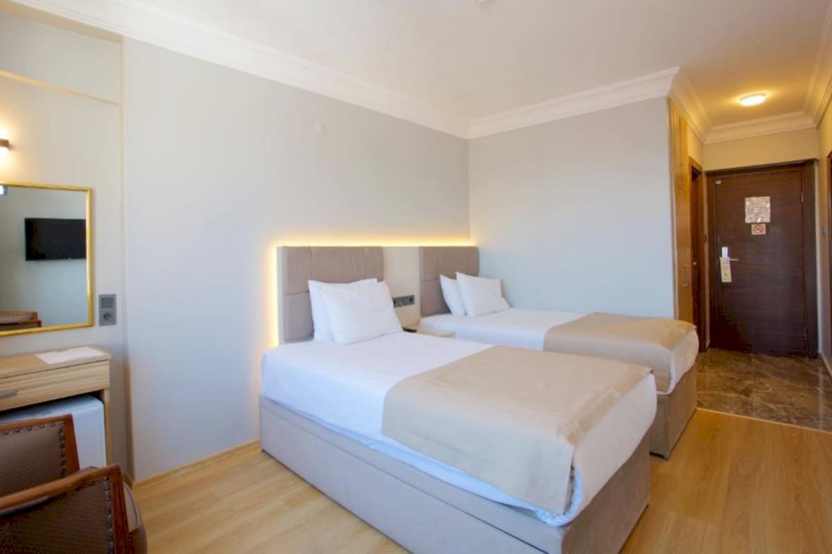 Una habitación de hotel con dos camas, un escritorio, una silla, un espejo y una puerta.