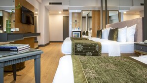 Una habitación de hotel moderna con una cama grande, una mesita de noche, un televisor y un espejo.